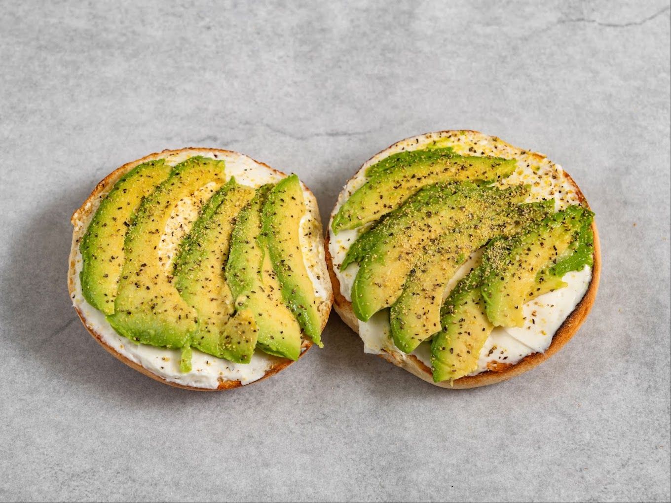 A bagel sliced and topped with fresh avocado